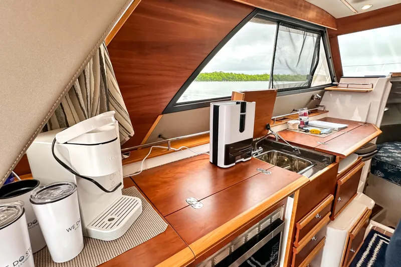  Yacht Photos Pics 2022 Cutwater 30 Command Bridge interior with kitchenette, featuring wood finish and modern appliances.
