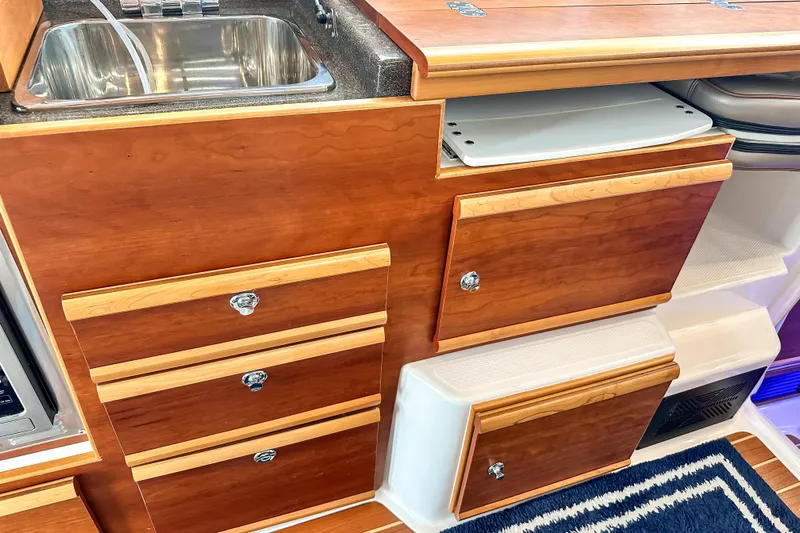  Yacht Photos Pics 2022 Cutwater 30 Command Bridge interior with wooden cabinetry and stainless steel sink.