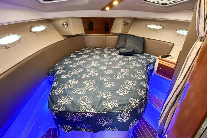  Yacht Photos Pics 2022 Cutwater 30 Command Bridge cabin with cozy bed, blue lighting, and porthole windows.