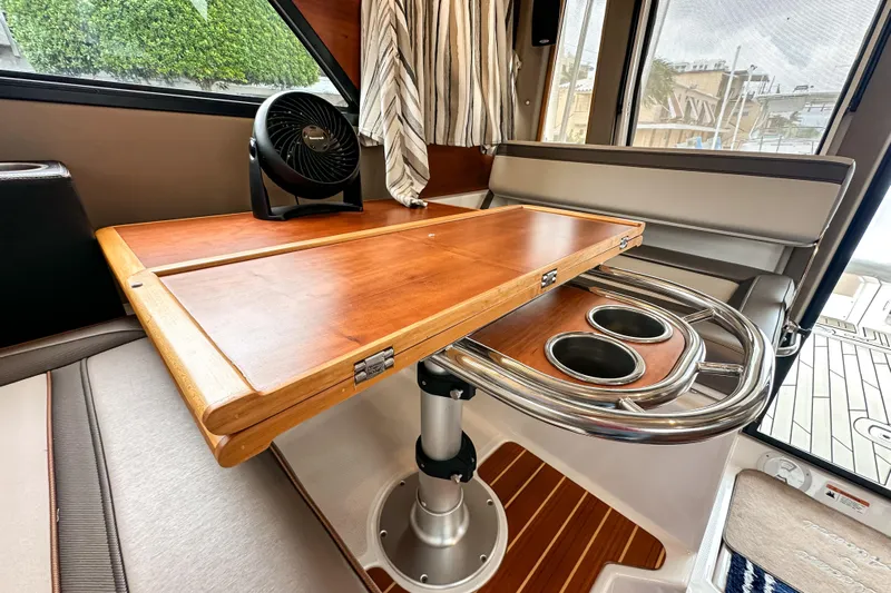  Yacht Photos Pics 2022 Cutwater 30 Command Bridge interior with wooden table and seating area.