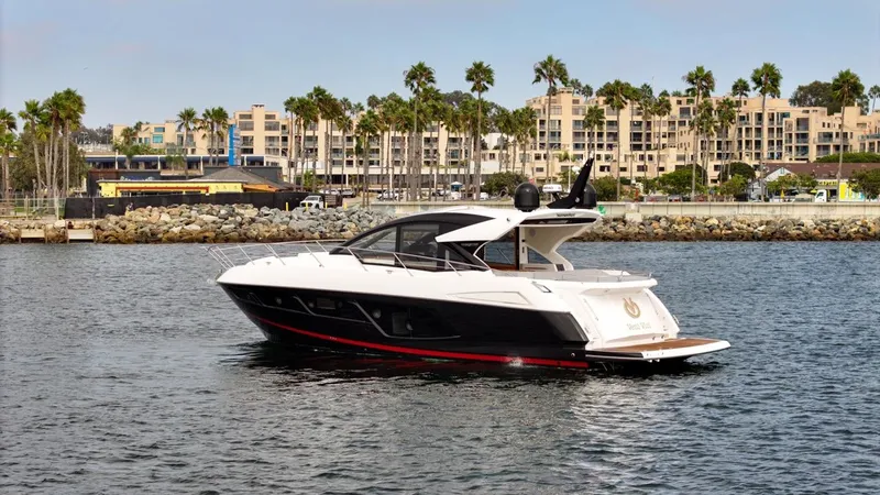Veni Vici Yacht Photos Pics 2019 Sunseeker Predator 57 yacht cruising near a coastal cityscape with palm trees.