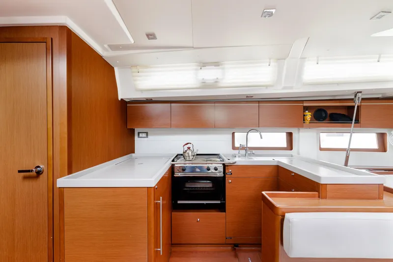  Yacht Photos Pics Modern kitchen interior of 2019 Beneteau Oceanis 51.1 yacht with wood cabinetry and appliances.