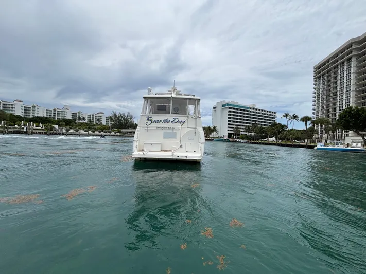 Seas The Day Yacht Photos Pics 2000 Silverton 453 Motor Yacht on waterway, surrounded by buildings and palm trees.