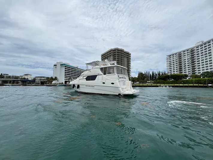 Seas The Day Yacht Photos Pics 2000 Silverton 453 Motor Yacht cruising near waterfront buildings under cloudy skies.
