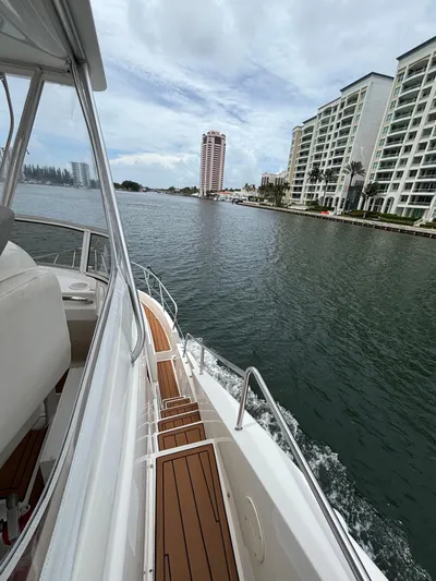 Seas The Day Yacht Photos Pics 2000 Silverton 453 Motor Yacht cruising near waterfront buildings under cloudy sky.