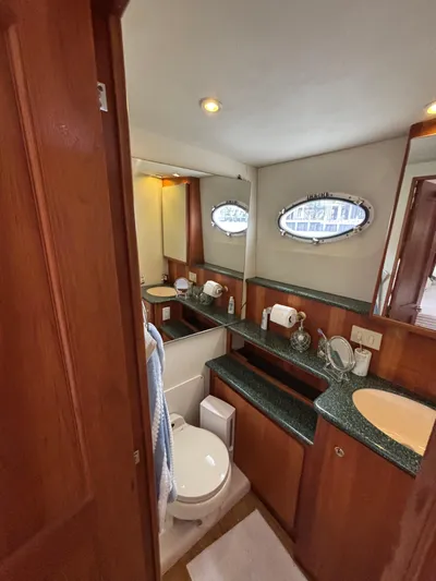 Seas The Day Yacht Photos Pics Luxurious bathroom in a 2000 Silverton 453 Motor Yacht with wood accents and oval windows.
