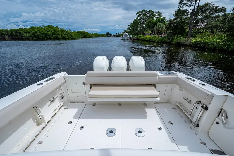 No Surrender Yacht Photos Pics 2017 Boston Whaler 370 Outrage boat on a serene river with lush greenery.