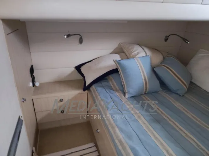  Yacht Photos Pics Cozy cabin interior of 2005 Uniesse 48 Open yacht with striped bedding and reading lights.