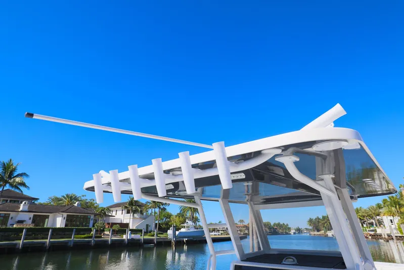  Yacht Photos Pics Invincible 37 Catamaran 2019 with rod holders, docked by waterfront homes under clear blue sky.