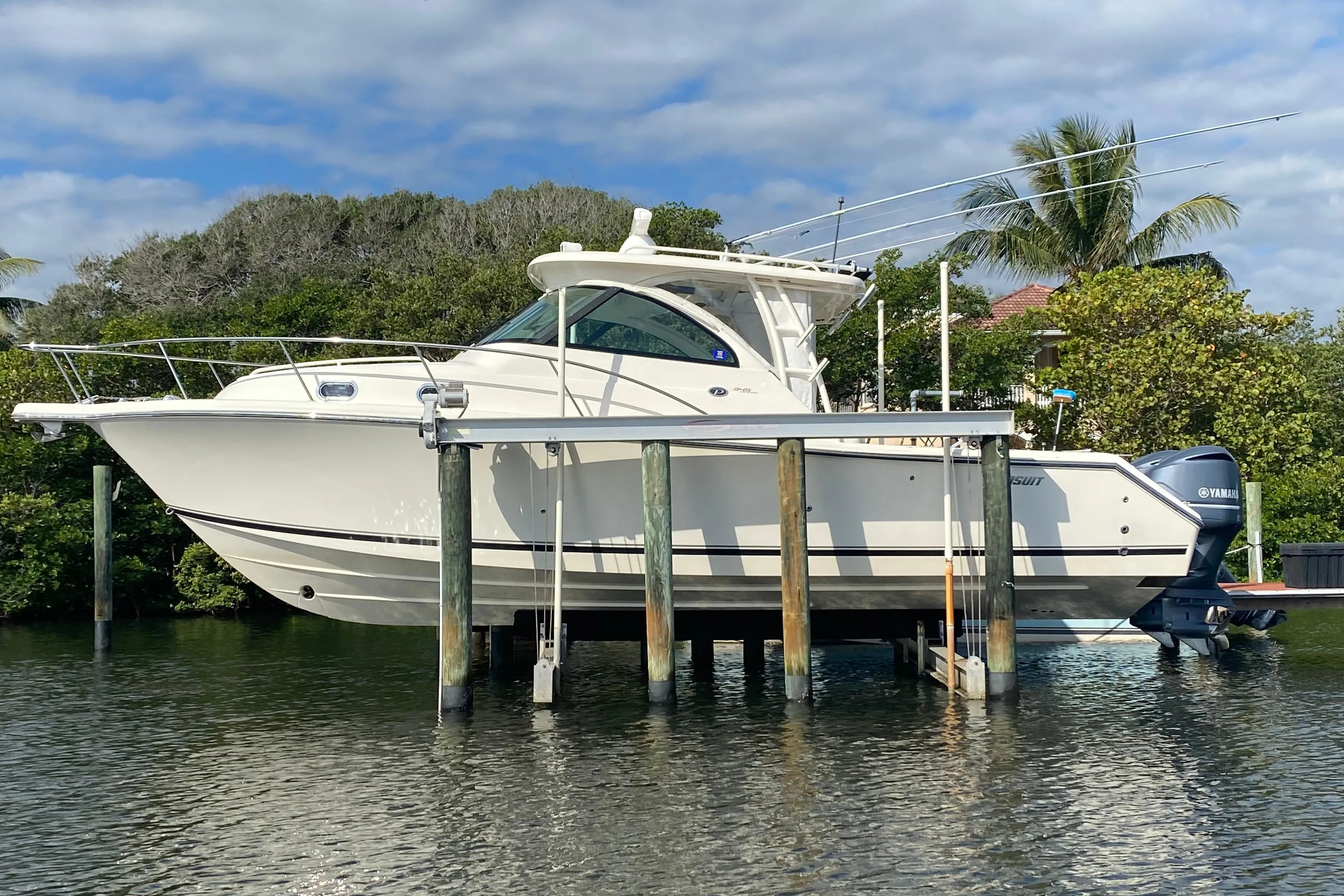 2012 Pursuit OS 345 Offshore boat on lift, surrounded by tropical scenery.