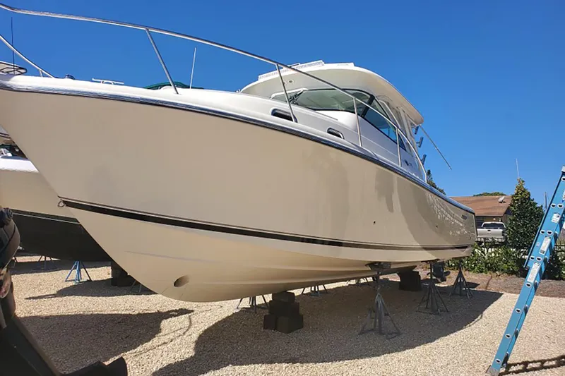 Little Solace Yacht Photos Pics 2012 Pursuit OS 345 Offshore boat on stands, clear sky background.