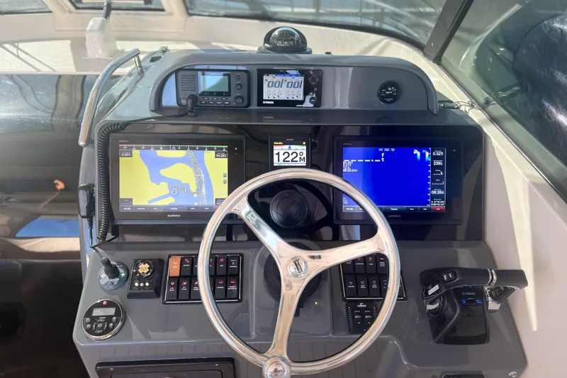 Little Solace Yacht Photos Pics Control panel of a 2012 Pursuit OS 345 Offshore boat with navigation screens and steering wheel.