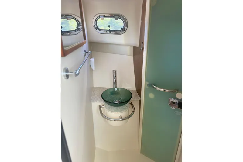 Little Solace Yacht Photos Pics Compact bathroom in 2012 Pursuit OS 345 Offshore boat with modern sink and porthole windows.