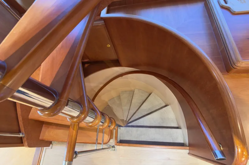 Family Time Yacht Photos Pics Curved wooden staircase inside 2006 Cheoy Lee 84 Bravo yacht, featuring elegant design.