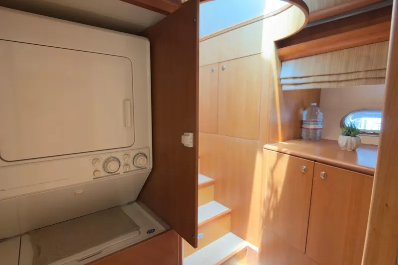 Family Time Yacht Photos Pics Laundry area inside 2006 Cheoy Lee 84 Bravo yacht, featuring wooden cabinetry and stairs.