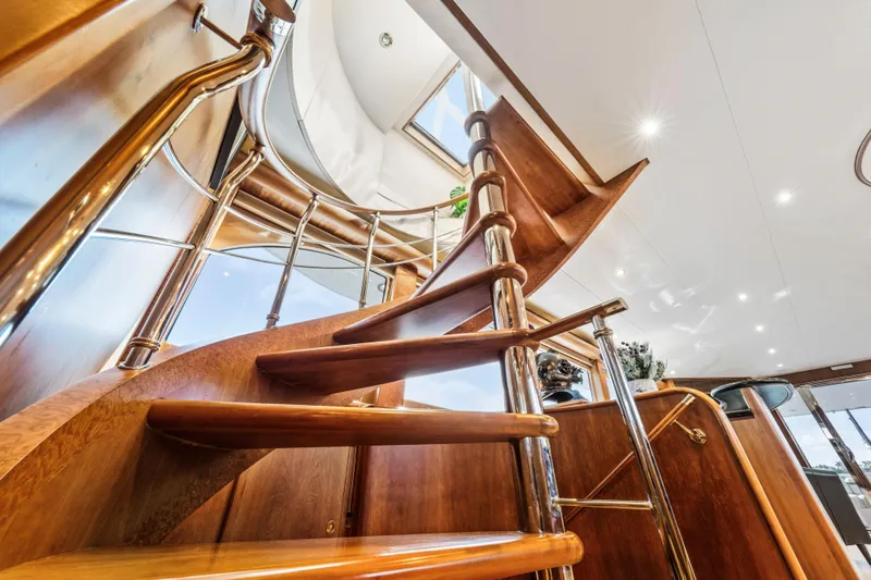 Family Time Yacht Photos Pics Luxurious wooden staircase inside 2006 Cheoy Lee 84 Bravo yacht, featuring elegant design and lighting.