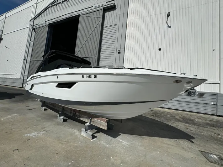 Pieseas Yacht Photos Pics 2019 Cruisers Yachts 338 Outboard, white hull, docked outside a large warehouse.