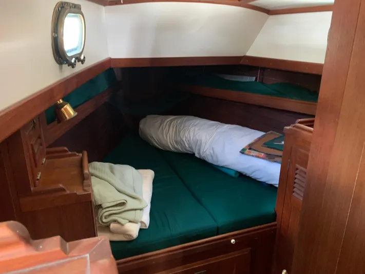 Isabella II Yacht Photos Pics Cozy cabin interior of 1988 Shannon 43 sailboat with green bedding and wooden furnishings.