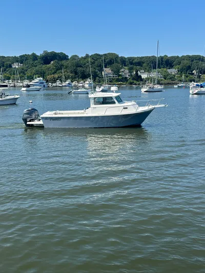  Yacht Photos Pics 2022 Parker 2520 XLD Sport Cabin boat on a calm lake with scenic background.
