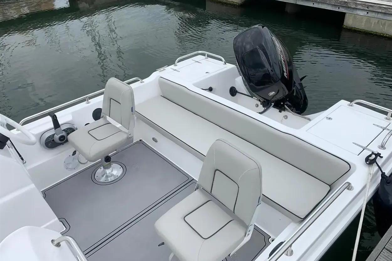 2022 Hunky Dory boat interior with seating and motor, docked on calm water.