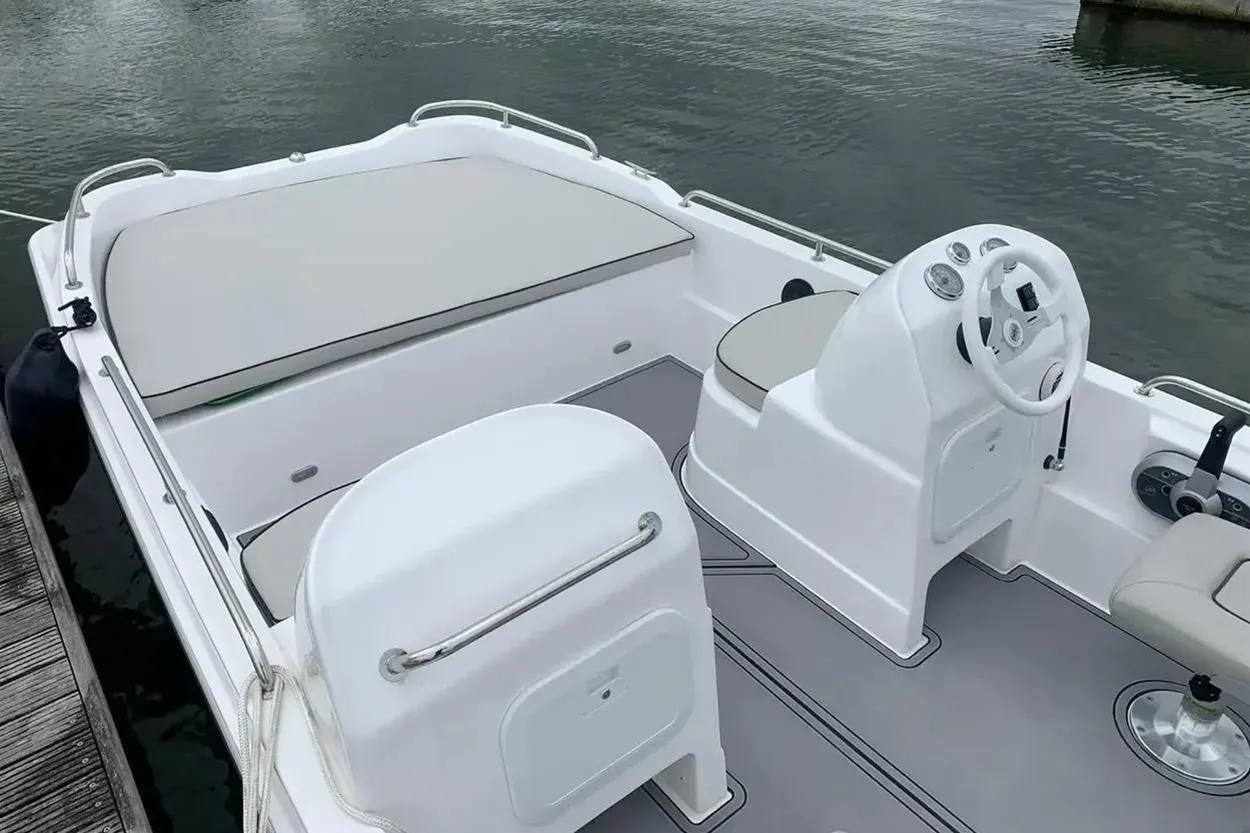 2022 Hunky Dory boat interior with steering console and seating, docked on calm water.