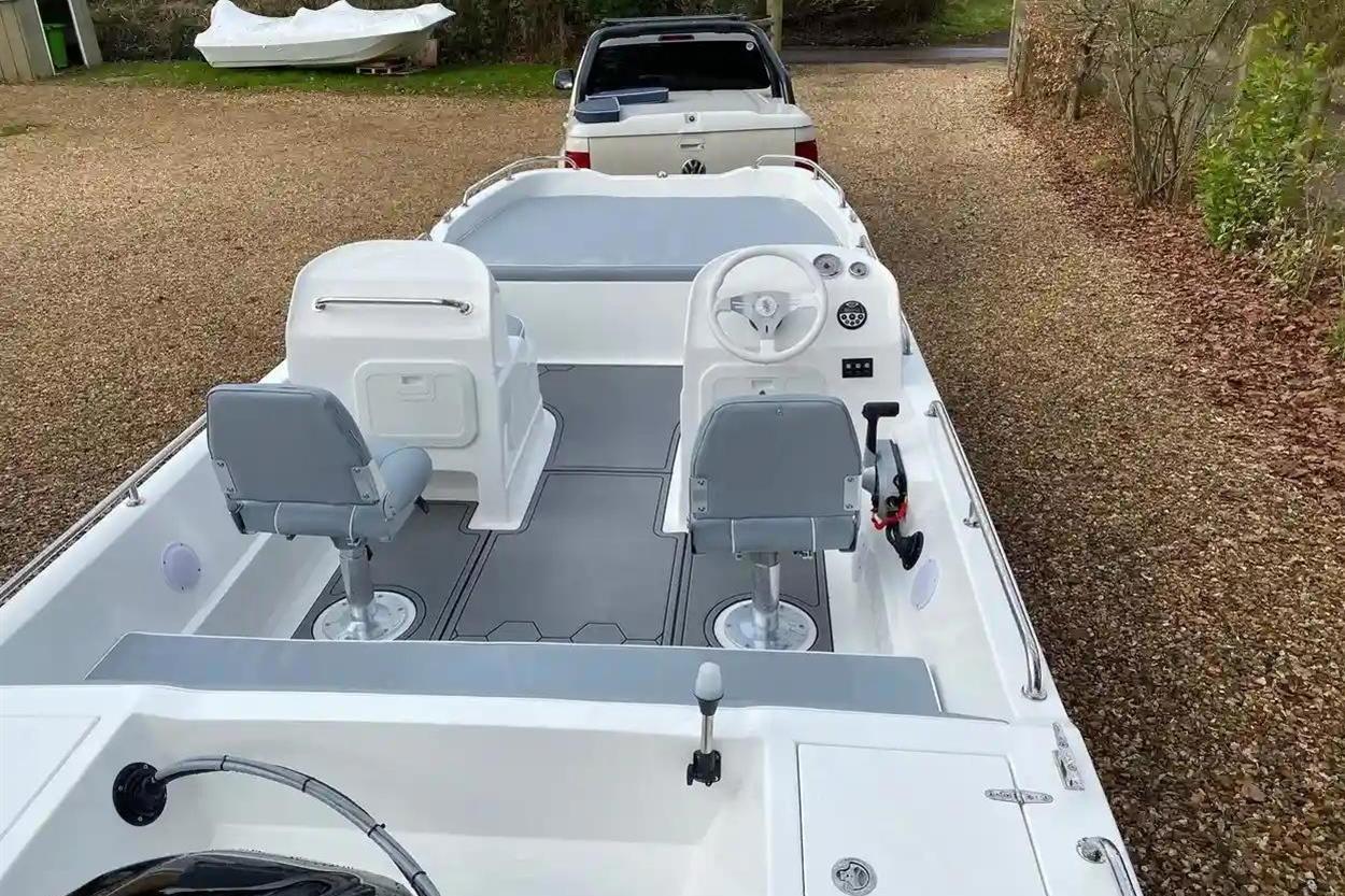 2022 Hunky Dory boat interior with dual seats and steering wheel, parked on gravel.