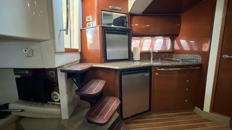 Lowest Price In Usa ! Yacht Photos Pics 2008 Sea Ray 380 Sundancer interior with kitchenette, featuring wood cabinetry and modern appliances.