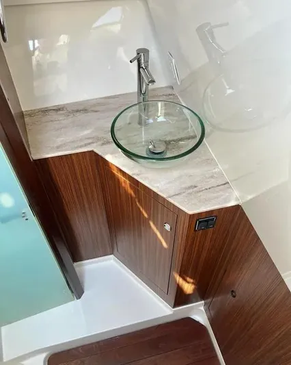  Yacht Photos Pics 2020 Pursuit DC 365 Dual Console bathroom with glass sink and wooden cabinetry.