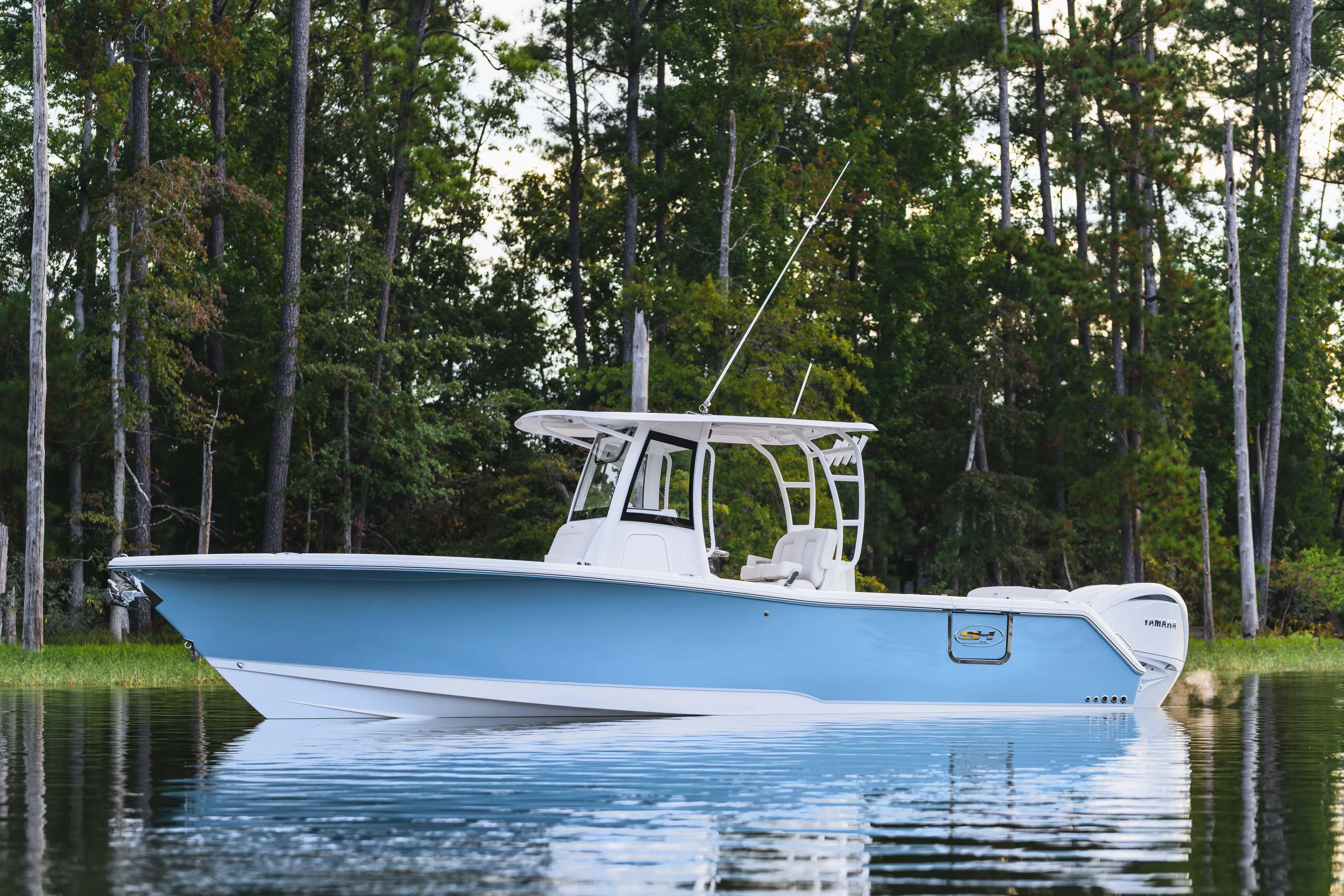  Yacht Photos Pics 2026 Sea Hunt Ultra 285 Coffin Box boat on calm water, surrounded by trees.