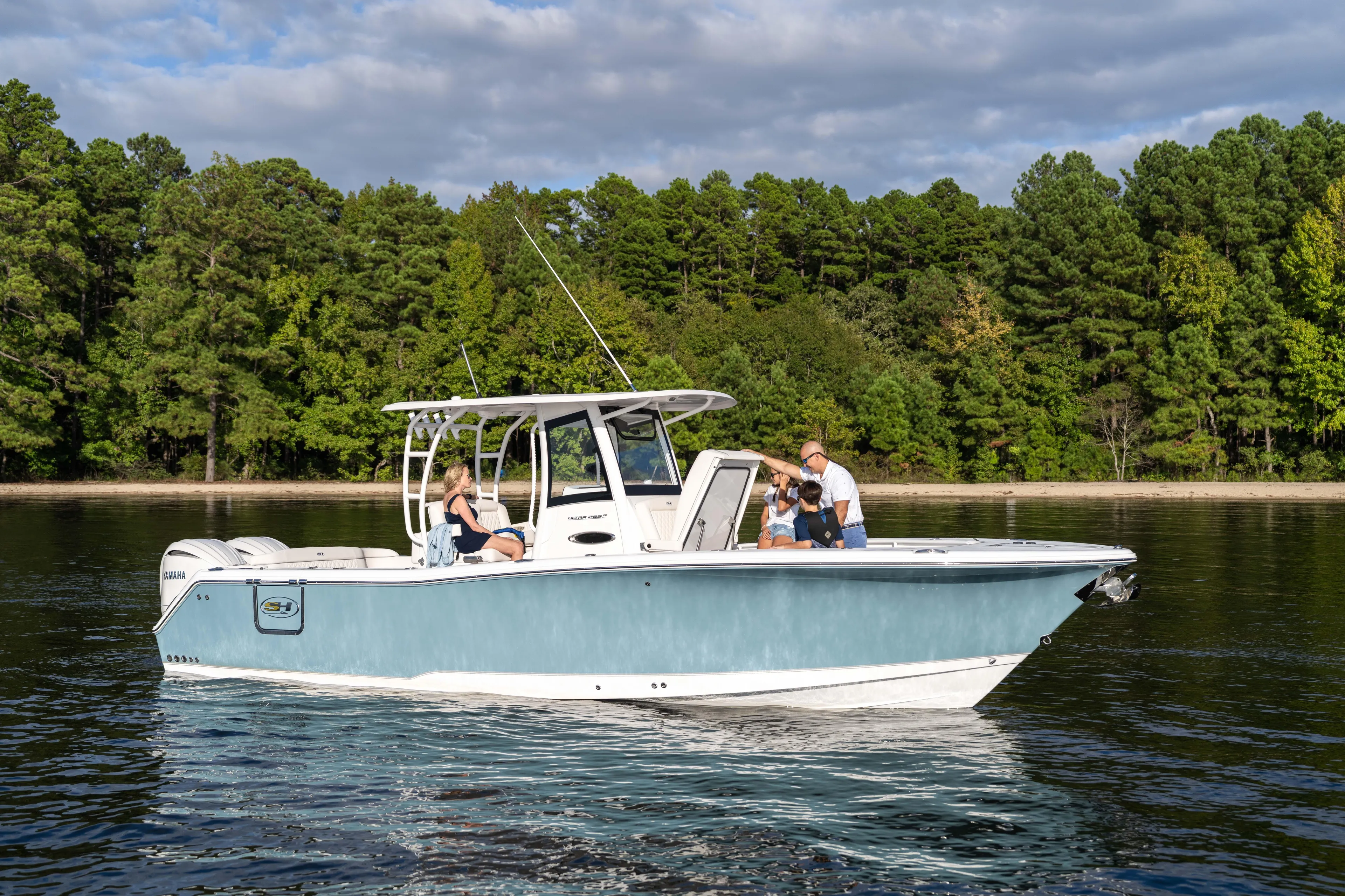  Yacht Photos Pics 2026 Sea Hunt Ultra 285 Coffin Box boat on a serene lake with lush forest backdrop.