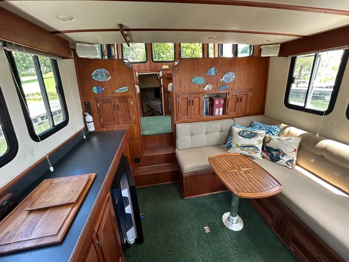 Forget Me Knot Yacht Photos Pics Interior of 2001 Nordic Tug 32 with cozy seating, wooden table, and decorative pillows.