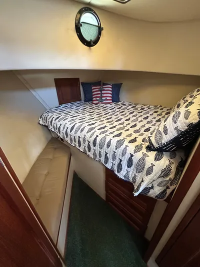 Forget Me Knot Yacht Photos Pics Cozy cabin interior of 2001 Nordic Tug 32 with patterned bedding and porthole window.