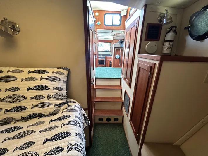 Forget Me Knot Yacht Photos Pics Cozy interior of 2001 Nordic Tug 32 with fish-patterned bedding and wooden cabinetry.