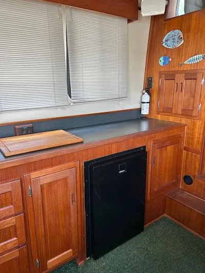 Forget Me Knot Yacht Photos Pics Interior of 2001 Nordic Tug 32 with wooden cabinetry and compact refrigerator.