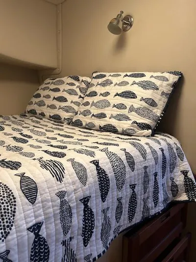 Forget Me Knot Yacht Photos Pics Cozy cabin bed in 2001 Nordic Tug 32, featuring fish-patterned bedding and wall-mounted reading light.