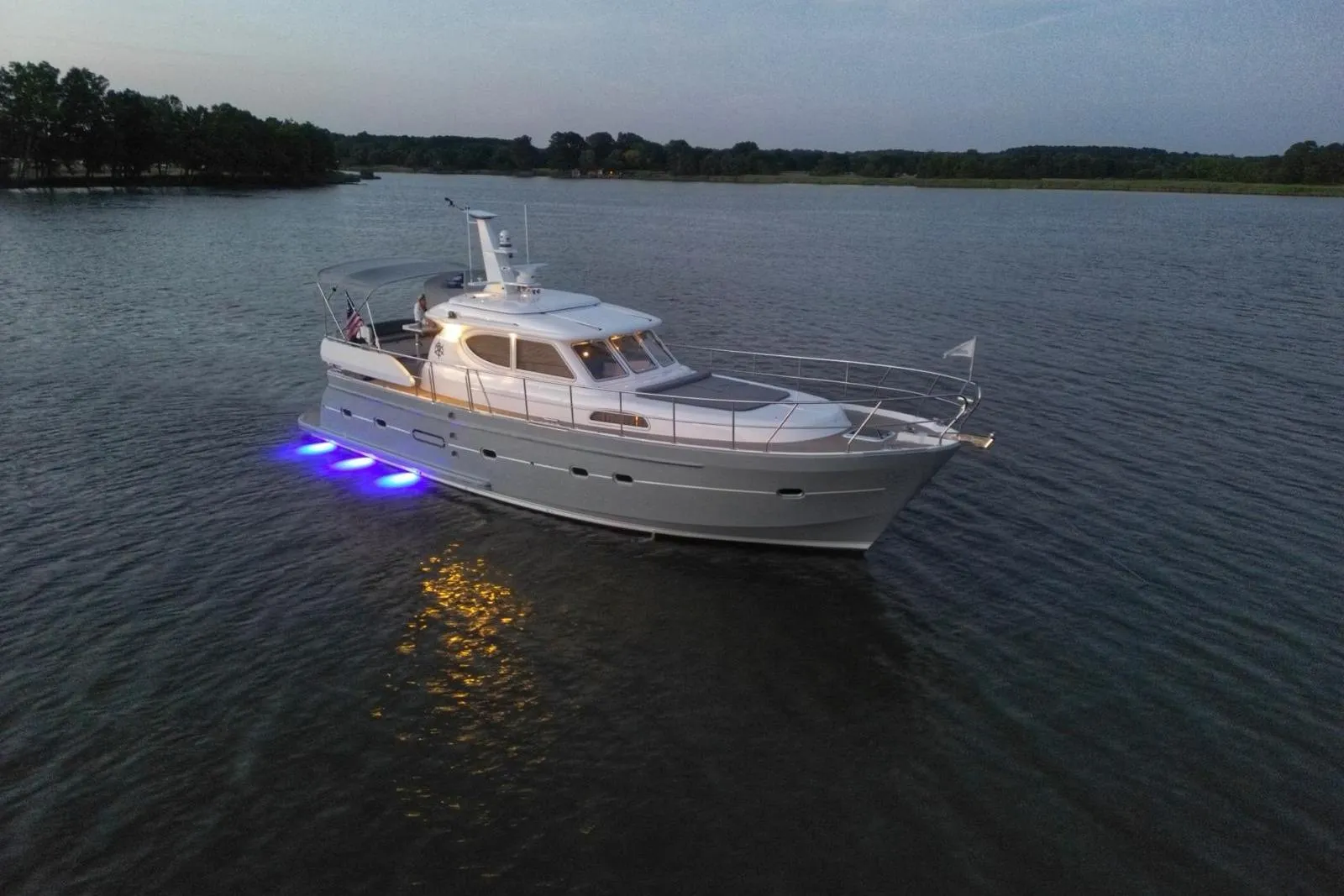 2024 Elling E4 yacht with blue underwater lights cruising on a serene lake at dusk.