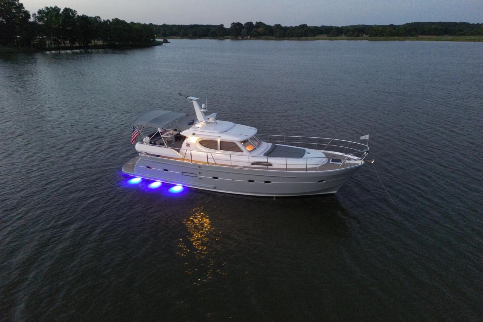 2024 Elling E4 yacht with blue underwater lights on a calm lake at dusk.
