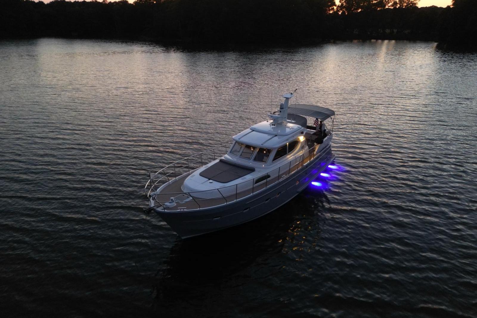 2024 Elling E4 yacht with blue underwater lights on a serene lake at dusk.