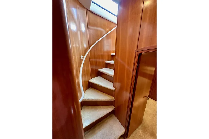 Seas The Day Yacht Photos Pics Curved staircase inside 2004 Meridian 580 Pilothouse yacht with wooden paneling.