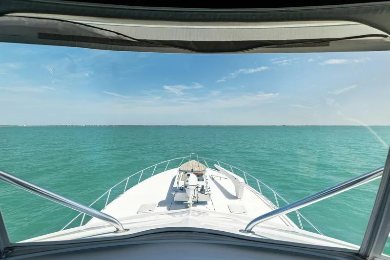 Big Game Yacht Photos Pics 2006 Hatteras 68 Convertible yacht cruising on turquoise waters under a clear blue sky.