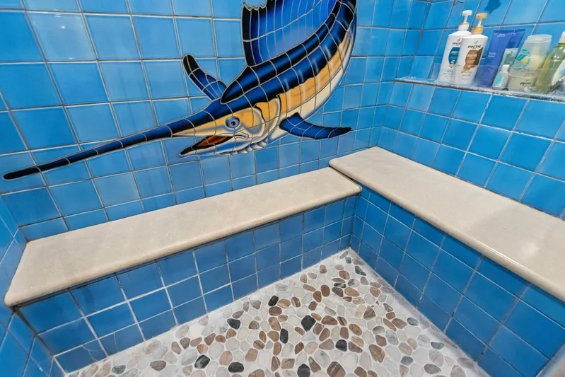 Big Game Yacht Photos Pics Blue-tiled shower with marlin mosaic, stone floor, and shelves on a 2006 Hatteras 68 Convertible.