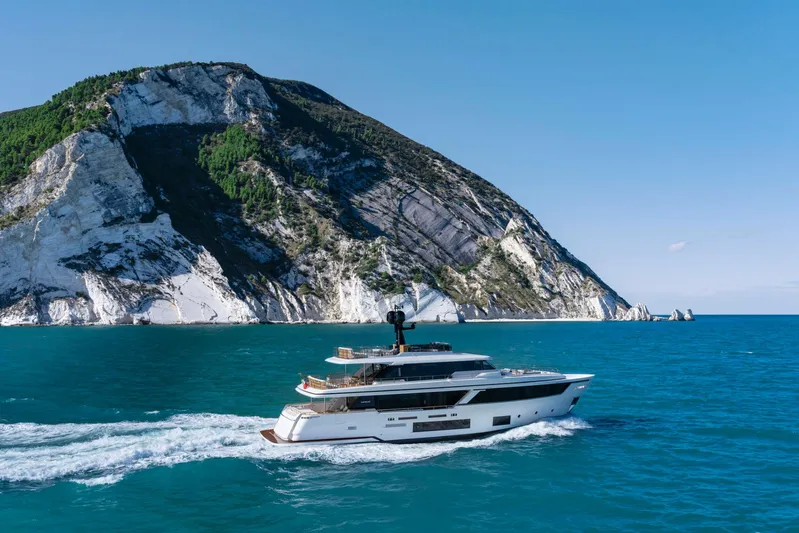  Yacht Photos Pics 2023 Navetta 30 luxury yacht cruising by scenic coastal landscape.