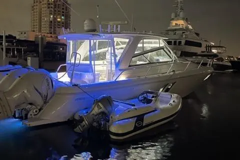 Her Salt Bouys Yacht Photos Pics 2019 Intrepid 475 Sport Yacht illuminated at night, docked with a small boat.