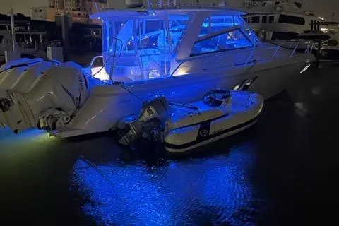 Her Salt Bouys Yacht Photos Pics 2019 Intrepid 475 Sport Yacht illuminated with blue lights at night, docked with a small boat.