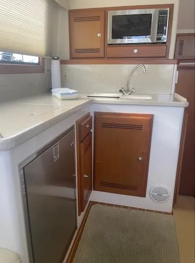 Lauralea Yacht Photos Pics 2006 Cabo 35 Flybridge Sportfisher kitchen with microwave, sink, and wooden cabinets.