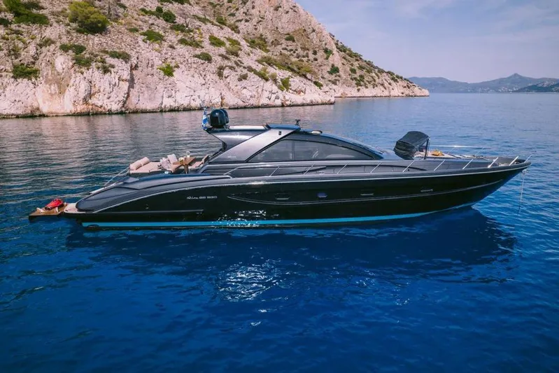  Yacht Photos Pics Luxury 2006 Riva 68 Ego yacht cruising in clear blue waters near rocky coastline.