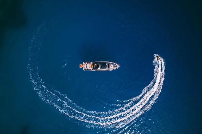  Yacht Photos Pics Aerial view of 2006 Riva 68 Ego yacht with jet ski circling in blue ocean.