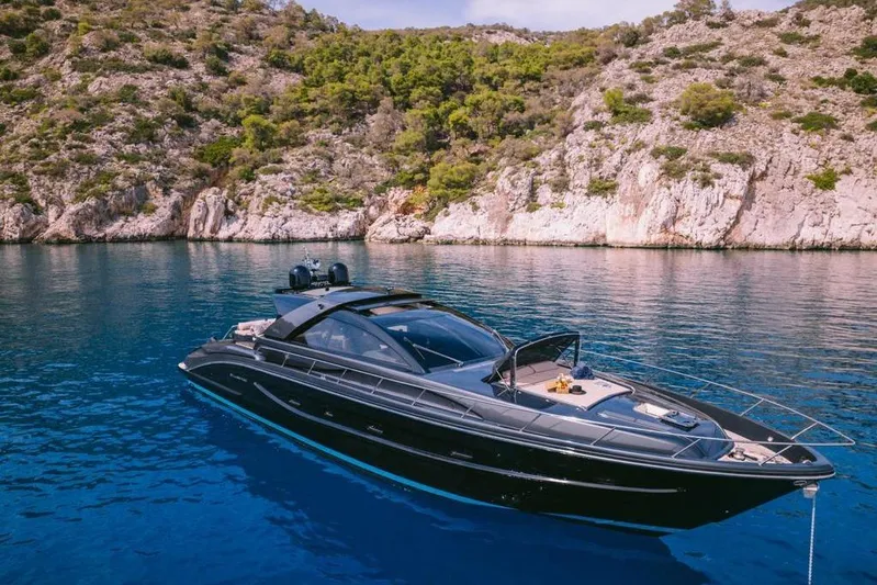  Yacht Photos Pics Luxurious 2006 Riva 68 Ego yacht anchored in serene, clear blue waters near rocky coastline.