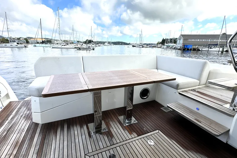 Lady Jane III Yacht Photos Pics Outdoor seating area on 2023 Prestige 520 yacht with wooden table and marina view.