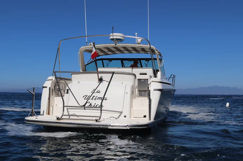 La Ultima Chica Yacht Photos Pics 1997 Tiara Yachts Express boat cruising on open water under clear blue sky.